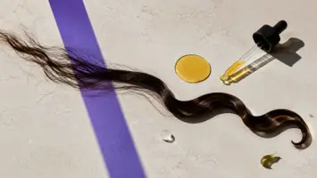 En tørr hårlokk som blir glattere ved siden av en gyllen oljedråpe og pipette